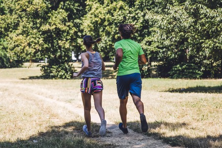 View at young couple running in the park on a sunny dayの写真素材