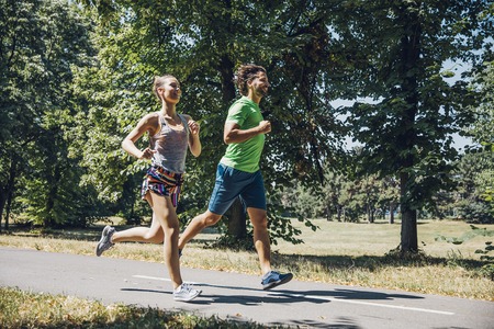 View at young couple running in the park on a sunny dayの写真素材