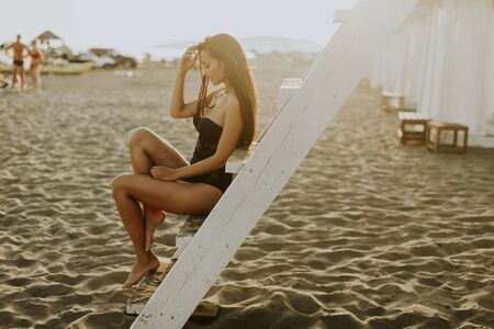 View at young woman posing on the beach by lifeguard observation towerの写真素材