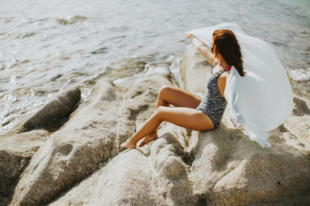 Pretty yung woman on the stony seaside beach at summer dayの写真素材