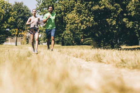 Young couple running in nature on a sunny summer dayの写真素材