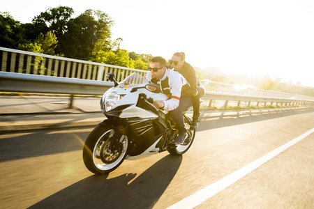 Young man and a woman on a motorcycle by day