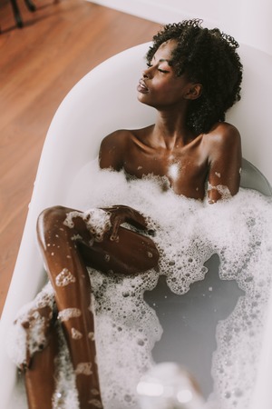 Top view at young afro american young woman laying in bath with foamの写真素材