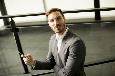 Portrait of happy smiling urban businessman using smart phone outsideの写真素材