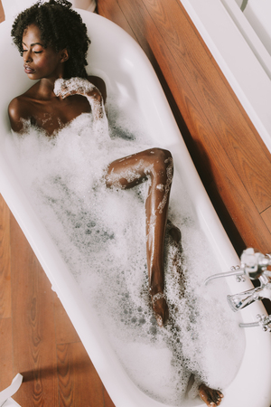 Top view at young afro american young woman laying in bath with foamの写真素材