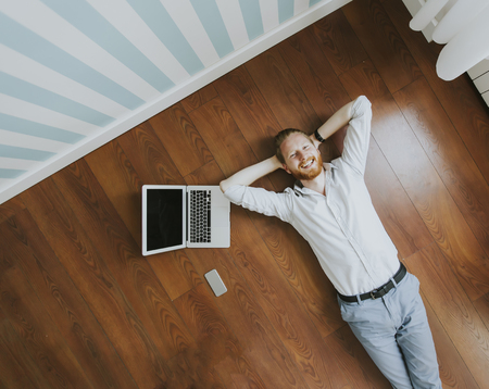 Young man with laptop computer while lying on the floor at homeのeditorial素材