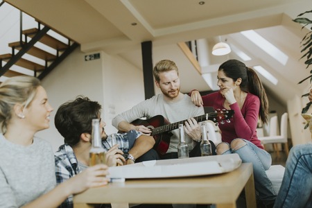 Group of young people having pizza party in the roomの写真素材