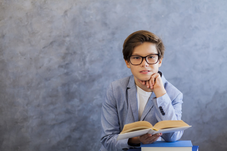 Portrait of cute teenage boy with glasses reading bookの写真素材