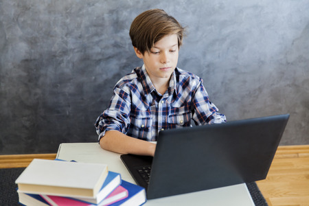 Teen age boy working on laptop at home