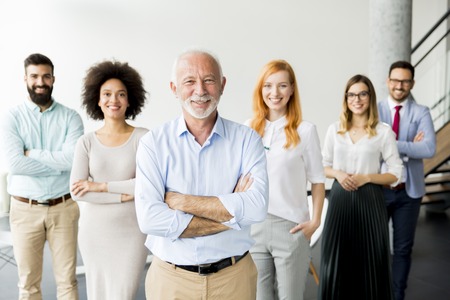 Young business people with senior colleague standing in the officeの写真素材
