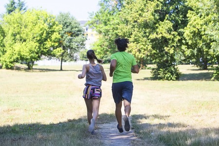 Back view at healthy, fit and  sportive couple running in park at summer morningの写真素材