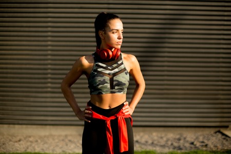 Pretty young woman takes a break after running in urban areaの写真素材