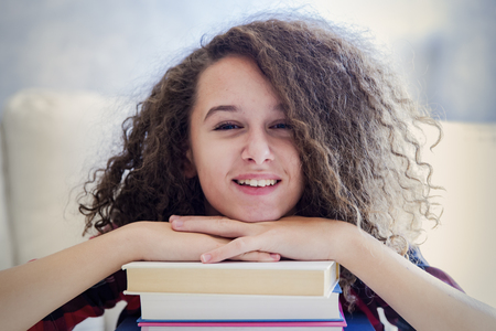 Portrait of teen girl resting on books in the roomの写真素材