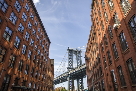 Manhattan bridge seen from a red brick buildings in Brooklyn street in perspective, New York, USA