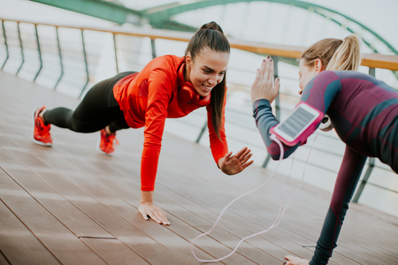 Young woman exercising with a personal trainer outside in the morningの写真素材