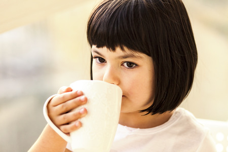 Portrait of pittle girl drinking milk or teaの写真素材