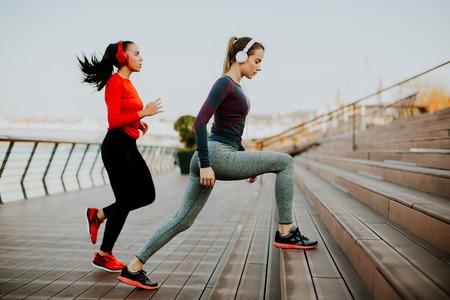 Young woman exercising with a personal trainer outside in the morningの写真素材