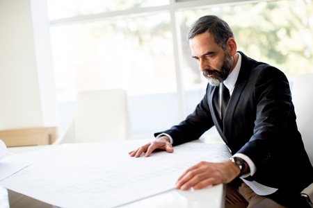Elegant smart looking Caucasian businessman sitting in office and reading documentの写真素材