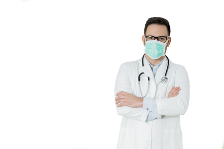 Portrait of handsome young doctor in white medical uniform and mask looking at camera against white backgroundの写真素材