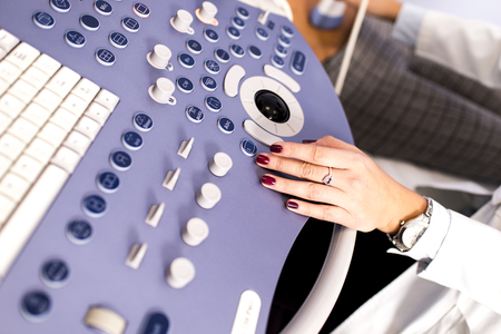 Close up view at doctors hands working on ultrasounds keyboard