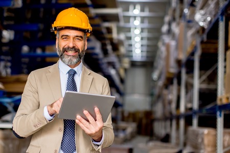 Handsome mature engineer in the warehouse with digital tablet