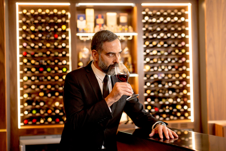 Handsome mature man tasting glass of red wineの写真素材