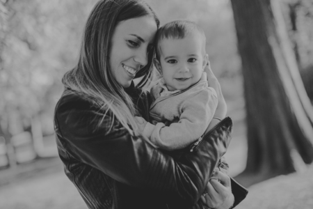Young mother and baby boy in autumn park at sunny dayの写真素材