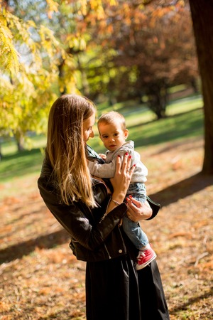 Happy young parents have fun with baby boy in autumn parkの写真素材