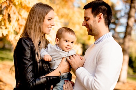 Happy family posing with baby boy in autumn park