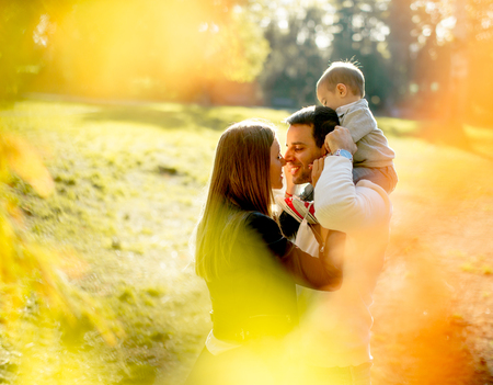 Happy young parents have fun with baby boy in autumn parkの写真素材
