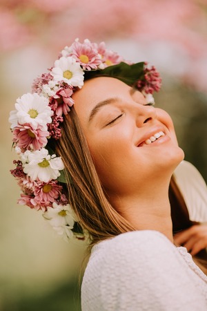 Portrait of young woman with wreath of fresh flowers on head in the parkの写真素材