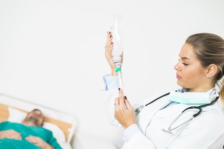 female doctor prepares an injection while the patient is in bed at clinicの写真素材