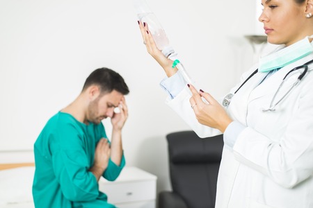 female doctor prepares an injection while the patient is in bed at clinic
