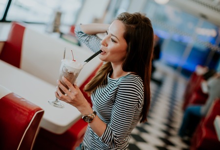 Woman with glass of milkshake at the dinerの写真素材