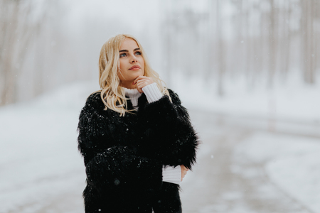 Pretty young blonde woman at snowy winter dayの写真素材