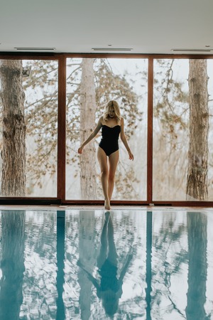 Pretty young woman standing by the swimming poolの写真素材