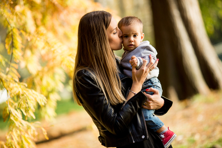 Portrait of young mother and baby boy in autumn parkの写真素材