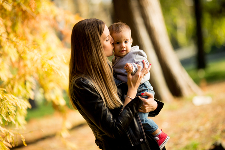 Portrait of young mother and baby boy in autumn parkの写真素材