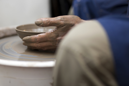 Close up detail view at an artist makes clay pottery on a spin wheelの写真素材