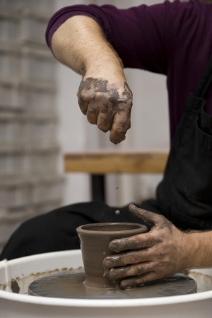 Close up detail view at an artist makes clay pottery on a spin wheelの写真素材