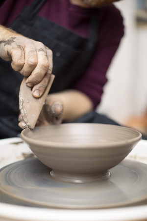 Close up detail view at an artist makes clay pottery on a spin wheelの写真素材