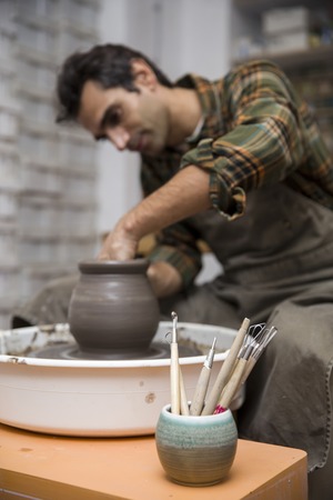 View at an artist makes clay pottery on a spin wheel in workshopの写真素材