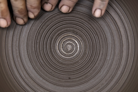 Close up detail view at an artist makes clay pottery on a spin wheelの写真素材