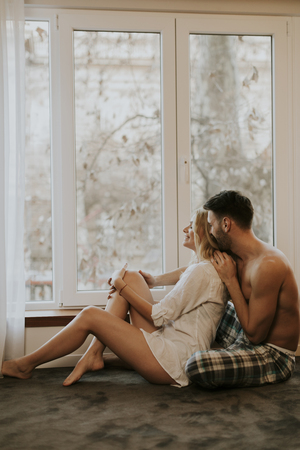 Young loving couple sitting on the floor in the roomの写真素材