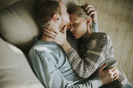 Top view at loving couple lying down on the sofa in the roomの写真素材