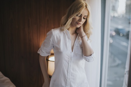 Portrait of attractive blonde woman by windowの写真素材