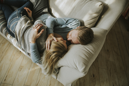 Top view at loving couple lying down on the sofa in the roomの写真素材