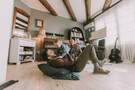Happy young family playing on the floor  in the roomの写真素材