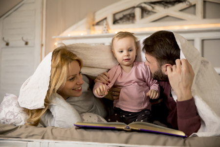 Young family having fun on the bed in the roomの写真素材
