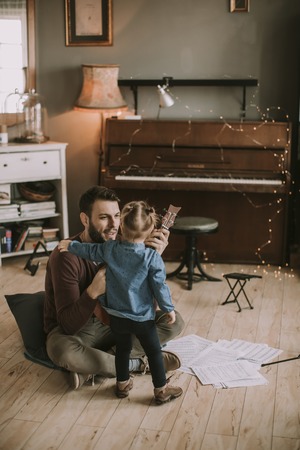 Father teaching daughter to play guitar in the room at homeの写真素材